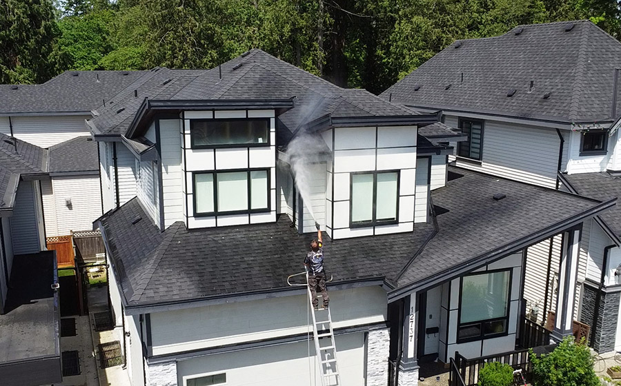 a team member soft washing a modern home in preparation for Diwali