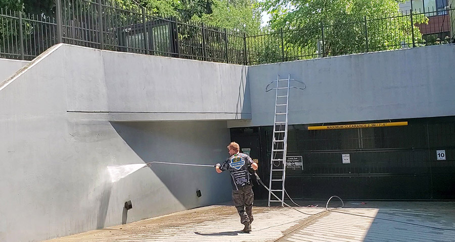 a clean squad employee pressure washing brick building siding